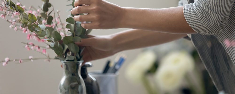 Hands adjusting flowers in vase